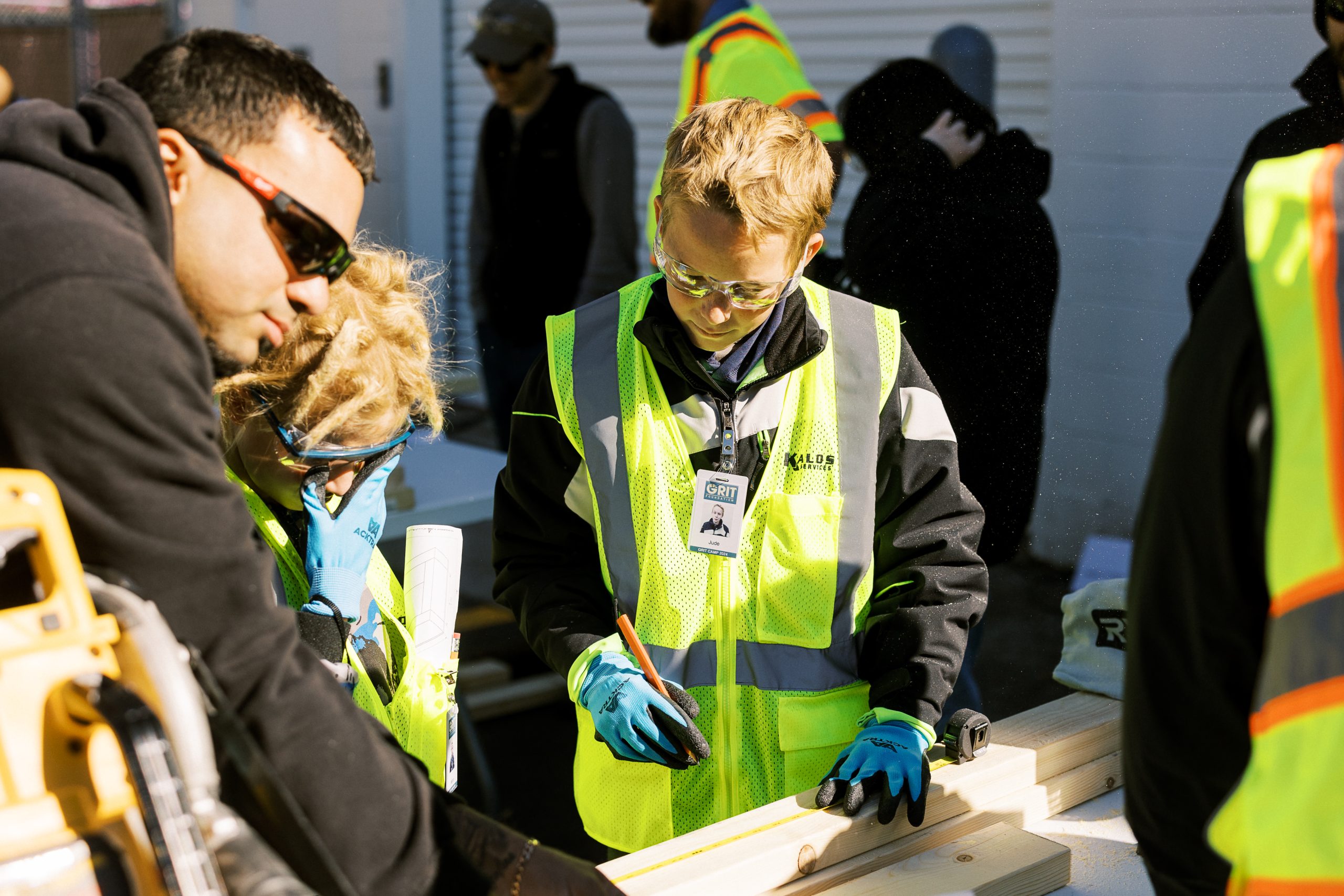 A mentor discusses a camp project with students at their workbench.