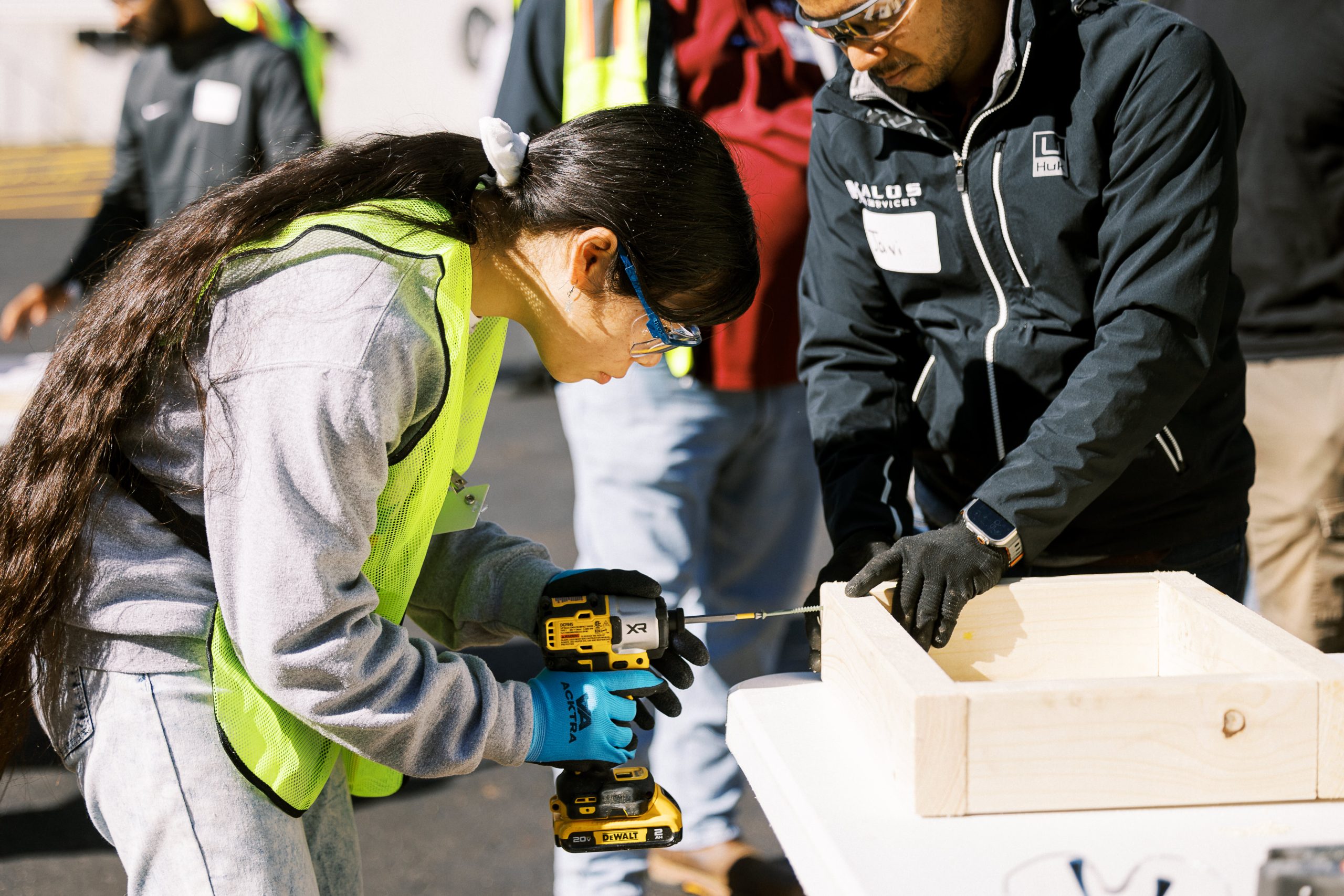 A mentor helps a student prepare a wood component for a camp project.